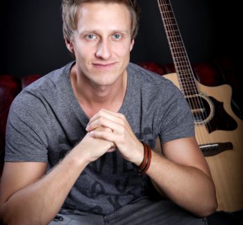 guy sitting down with guitar background