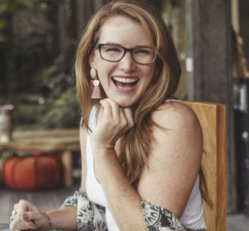 red haired woman with eyeglasses looking happy