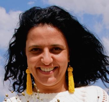 headshot photo of a woman smiling with yellow earrings